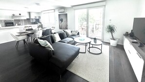 A modern living room with a sofa, coffee table, and a dining area with chairs and a table. - Au Coeur du Vignoble, Magnifique vue Avec Terrasse (Westhalten)