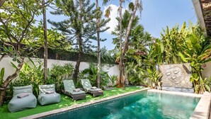 A pool area with lounge chairs and a decorative wall. - Villa Utara - Two Bedroom Villa, Sleeps 4 (Seminyak)