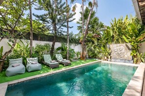 Un área de piscina con sillas de descanso y un muro decorativo.