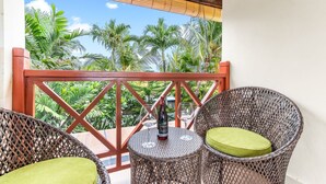A balcony with wicker chairs and a small table, overlooking a tropical garden. - Villa Utara - Two Bedroom Villa, Sleeps 4 (Seminyak)