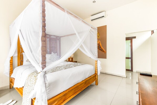 Una cama con dosel y estructura de madera, ropa de cama blanca, una mesita de noche y un equipo de aire acondicionado instalado en la pared.