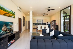 Un salon moderne avec un canapé, un téléviseur et des meubles de rangement.
