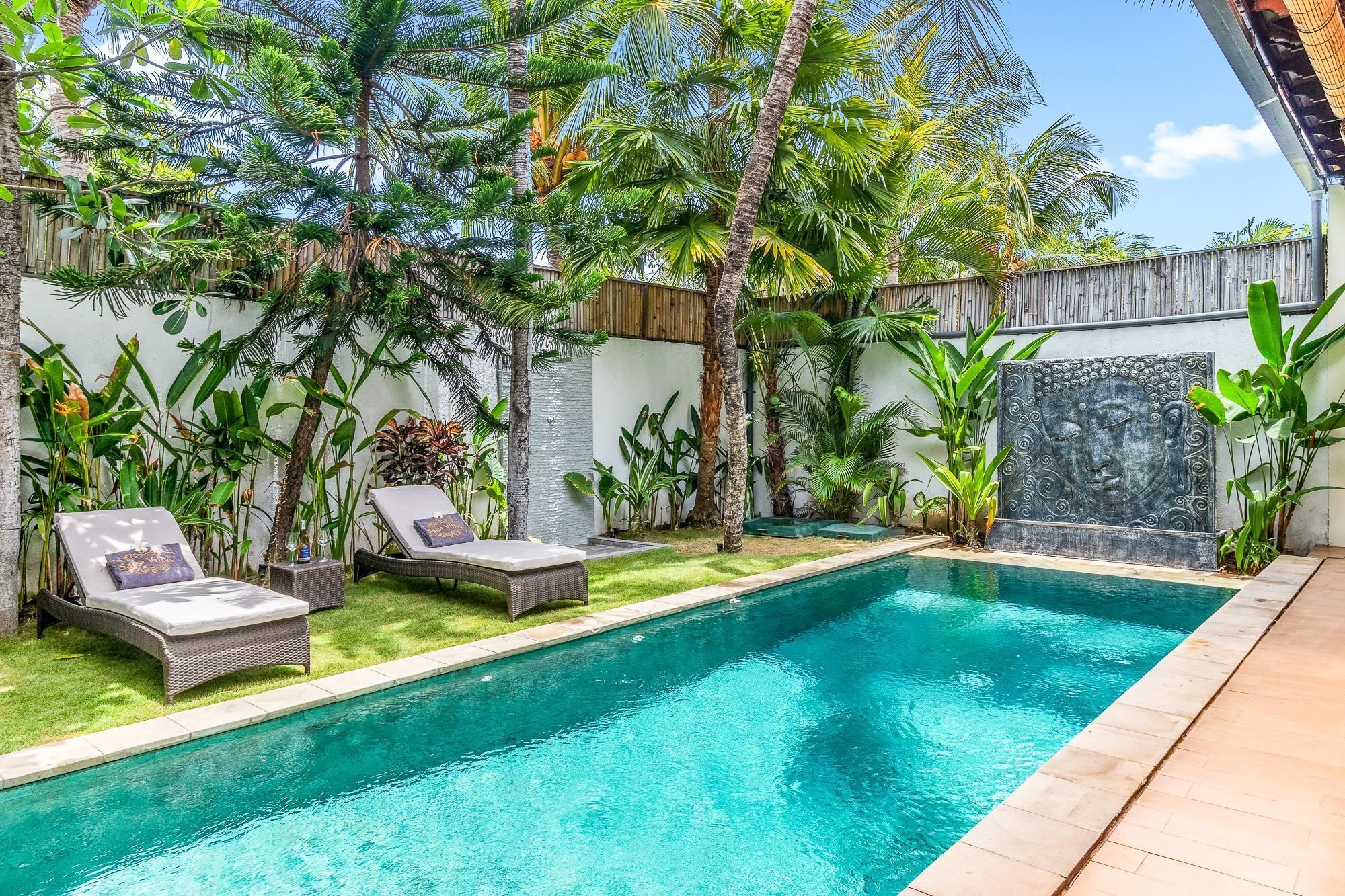 Une piscine dotée de chaises longues et agrémentée de plantes tropicales.