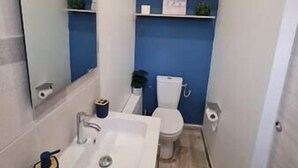 Un bany amb un lavabo blanc, un vàter i prestatges amb plantes.