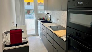 Ett modernt kök med en inbyggd ugn, en kaffemaskin och utsikt över balkongen.