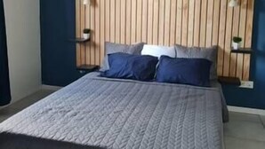 Un dormitorio con cama, dos mesitas de noche y un revestimiento de listones de madera.
