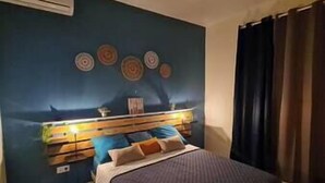 A bedroom with a bed, a wall-mounted air conditioner, and a window with curtains. - VBF - Cosy Apartment (Fort-de-France Bay)