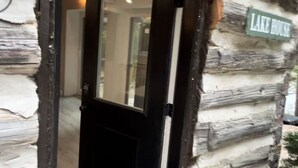 A log cabin with a black door and a small porch area. - New 2-bedroom cottage in Bancroft Ontario, fully renovated on the lake (MONT)