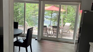 A kitchen with a dining area, large sliding glass doors, and a view of outdoor patio furniture. - New 2-bedroom cottage in Bancroft Ontario, fully renovated on the lake (MONT)