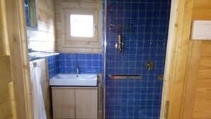 A small bathroom with a sink, mirror, and blue-tiled shower enclosure.