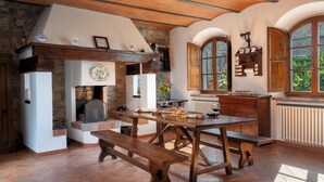 A rustic kitchen with a stone wall, wooden beams, and a large window with a view of greenery.