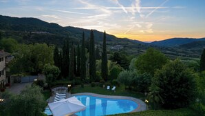 A pool surrounded by greenery, with a view of distant hills and a clear sky.