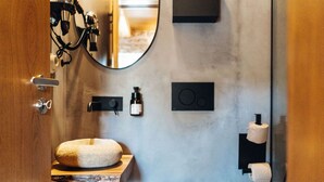 A bathroom with a round stone sink, a mirror, a towel rack, and a toilet paper holder. - a small, very elegant and cosy studio loft of almost 14m2 (Sortelha)