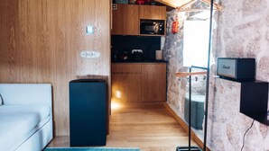 A compact living space with a kitchenette, a compact fridge, a sofa, and a speaker. - a small, very elegant and cosy studio loft of almost 14m2 (Sortelha)