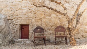 A stone wall with a red door and two wooden benches under a tree. - a small, very elegant and cosy studio loft of almost 14m2 (Sortelha)