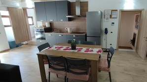Una cocina moderna con armarios grises, un refrigerador de acero inoxidable y un comedor con mesa y sillas.