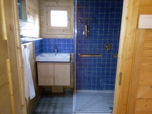 Ein kleines Badezimmer mit Waschbecken, Spiegel und Duschkabine mit blauen Fliesen.
