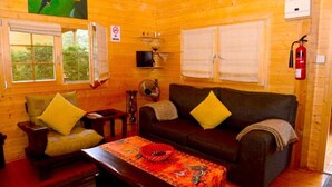 Ein gemütliches Blockhaus-Interieur mit einer Couch, einem Sessel und einem Tisch mit einer dekorativen Schale.