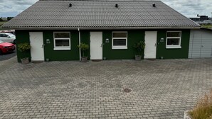 Un edificio verde con techo de tejas, puertas numeradas y un camino de entrada pavimentado.