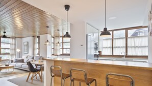 A modern kitchen with a wooden countertop, bar stools, and pendant lighting.