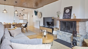 A modern living room with a fireplace, a television, and a dining area.
