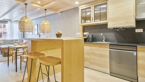 Une cuisine moderne avec des meubles en bois, un lave-vaisselle encastré et un coin bar avec des tabourets.