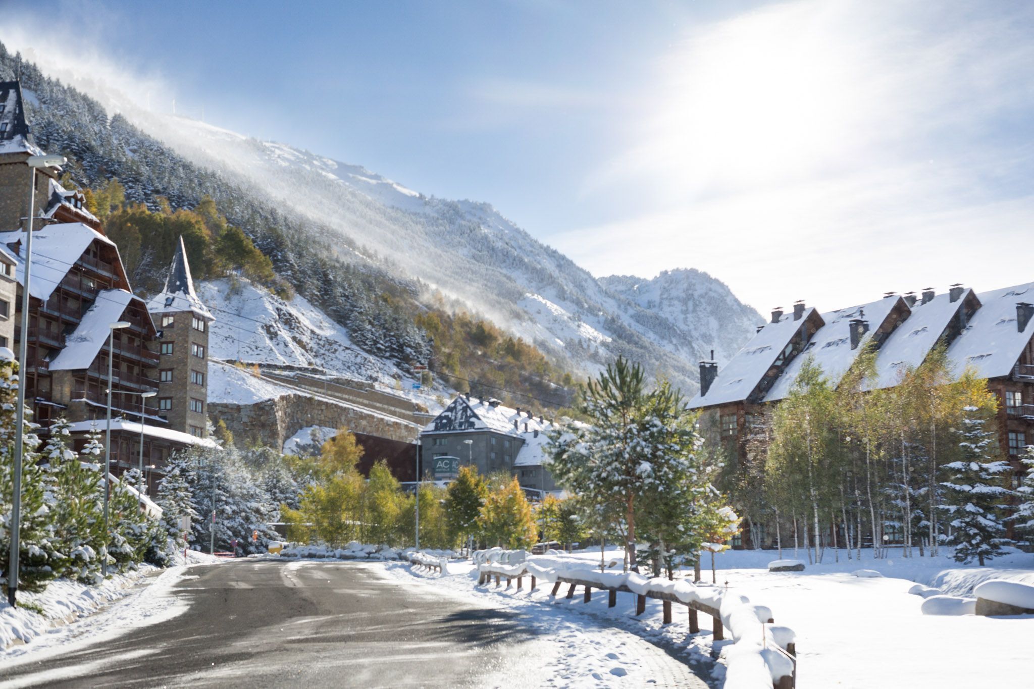 A snow-covered mountain town with a road leading to a building with a sign 'AC'.