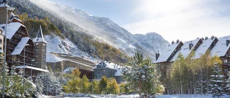 A snow-covered mountain town with a road leading to a building with a sign 'AC'.
