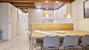 A modern kitchen with wooden cabinets, a wooden dining table, and grey chairs. - Luderna - Apartamento Val de Ruda B92 Ticolet (Baqueira)