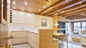 A modern kitchen with wooden cabinets and a dining area with a table and chairs. - Luderna - Apartamento Val de Ruda B92 Ticolet (Baqueira)