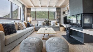 A modern living room with a sofa, ottomans, a coffee table, and a fireplace. - Luderna - Tríplex Amitges (Bagergue)