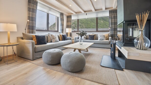 A modern living room with a sofa set, ottomans, a coffee table, and a fireplace. - Luderna - Tríplex Amitges (Bagergue)