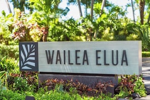 A sign with the text 'WAILEA ELUA' surrounded by greenery.