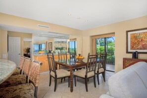A dining area with a glass-top table, wooden chairs, and a view of the outdoors. - KBM Resorts | FREE CAR | Wailea Elua | 2-Bedroom Condo Condo with Luxury Amenities! WEV-2009 (Wailea)