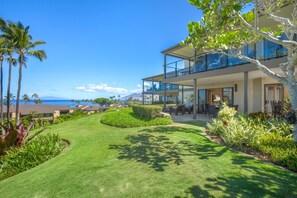 A modern two-story house with a large glass balcony overlooking a lush garden and a view of the ocean. - Wailea Elua Village | Ocean View 2 BR | Car Incl. w/ 6+ Nights | WEV-2009 by KBM (Wailea)