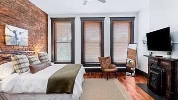 Une chambre à coucher avec un lit, une chaise, une télévision et une cheminée.