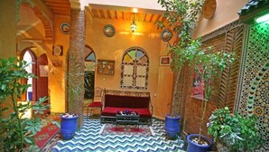 A cozy interior with a patterned floor, a red sofa, and potted plants. - Riad Taghazoute (Marrakech)