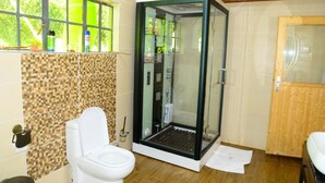 A bathroom with a glass-enclosed shower, a toilet, and a sink.