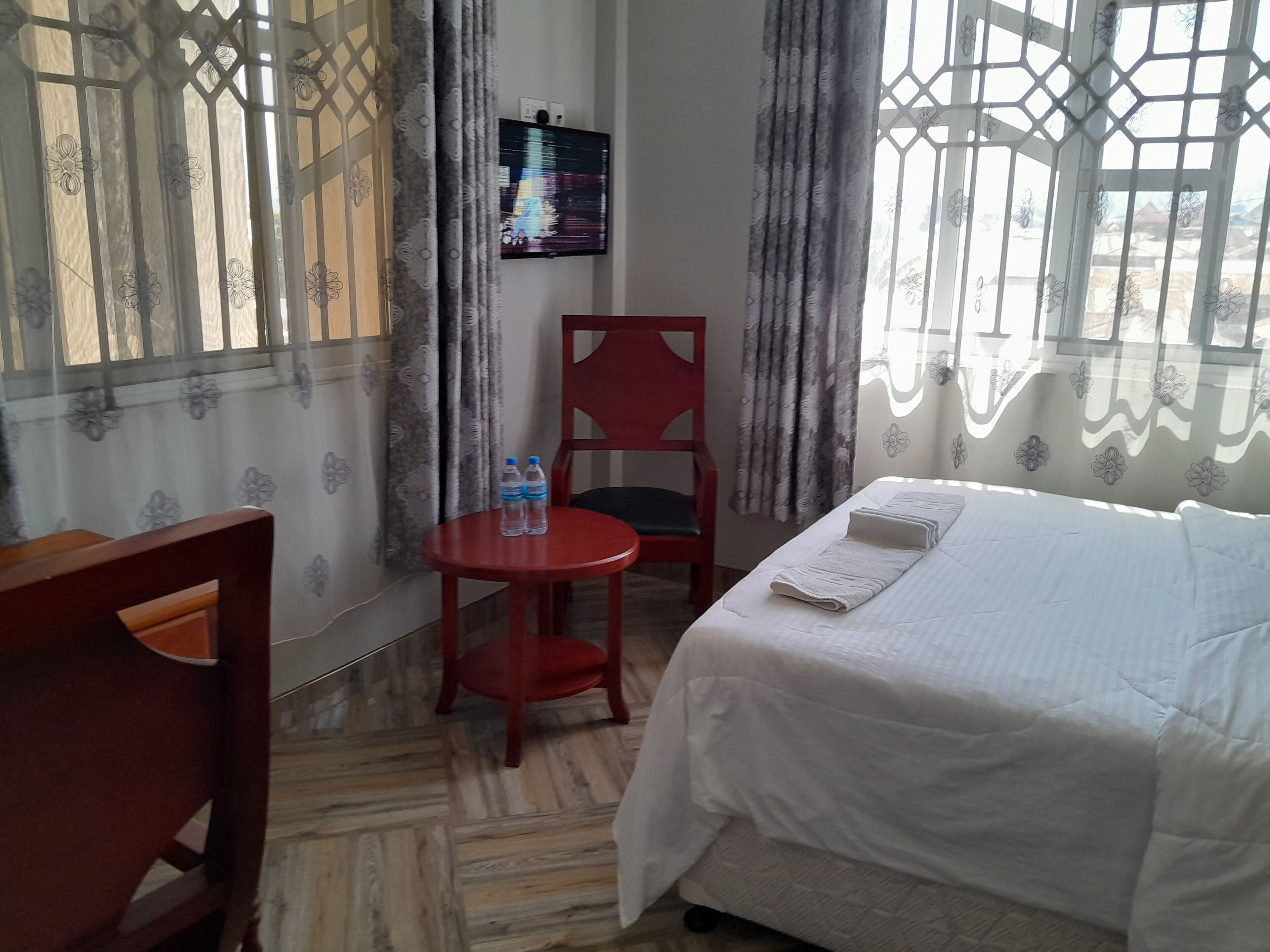Una habitación de hotel con una cama, un escritorio, una silla y una mesita con dos botellas.