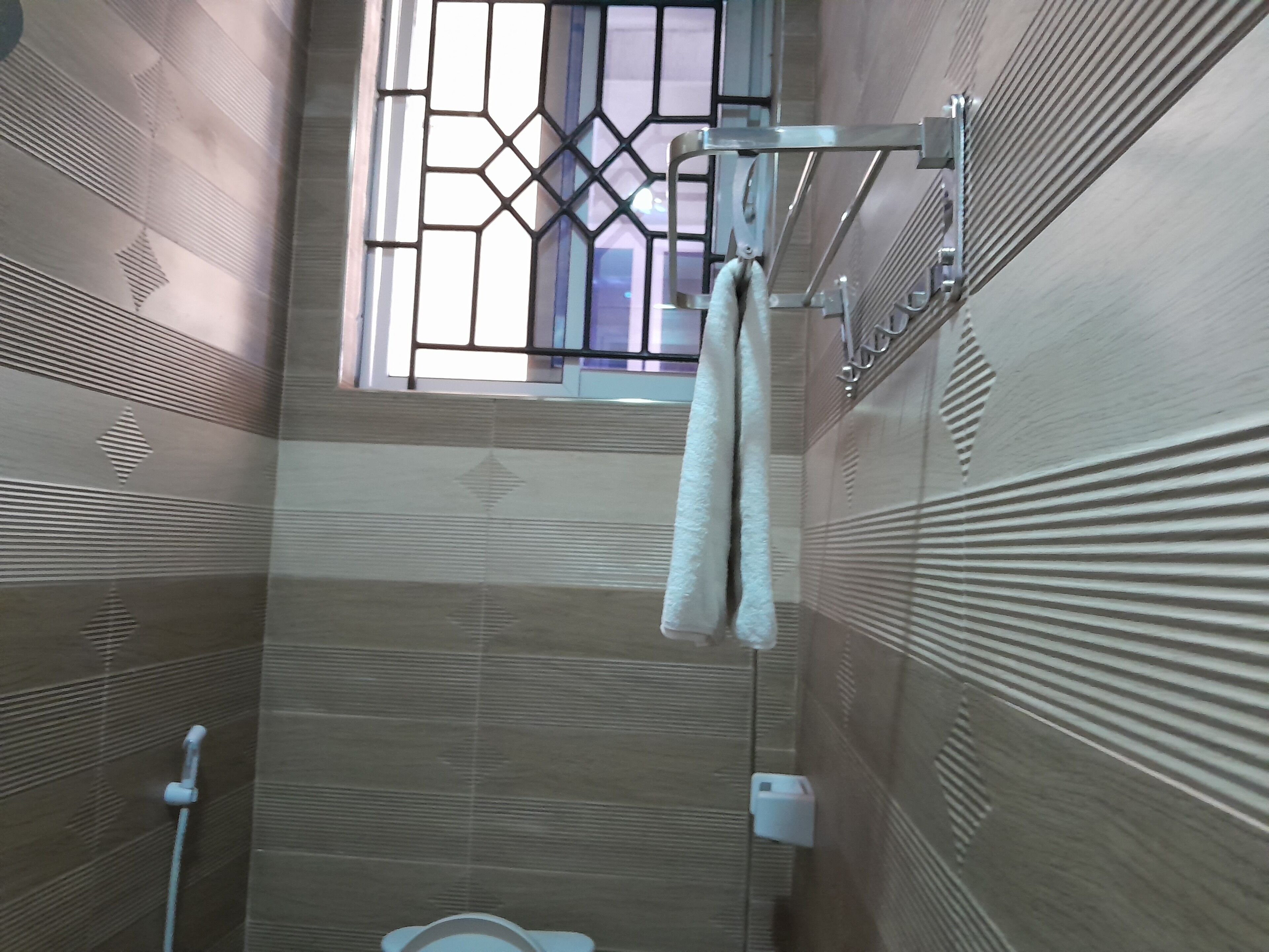 Ein Badezimmer mit Fenster, Handtuchhalter und Duscharmaturen.