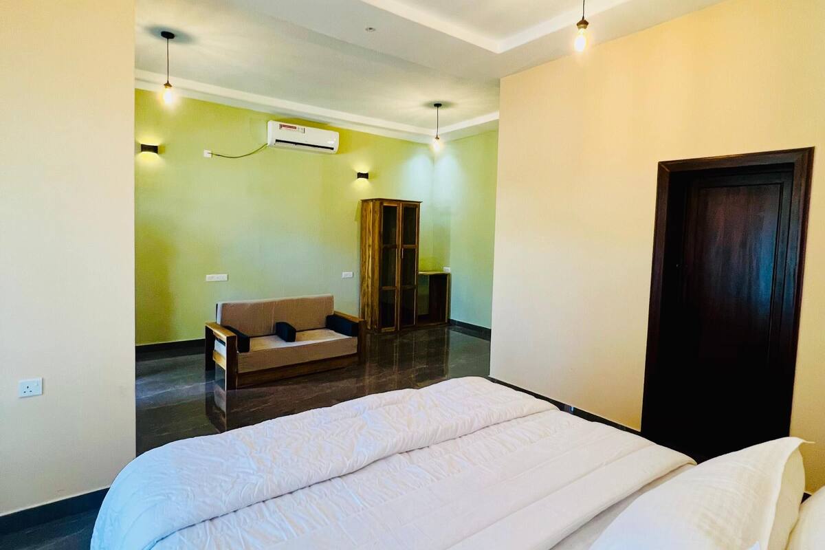 A hotel room with a large bed, a sofa, a desk, and a wardrobe.
