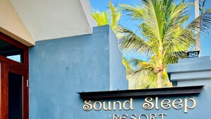 Señal para 'Sound Sleep Resort', con una pared azul y una palmera al fondo.