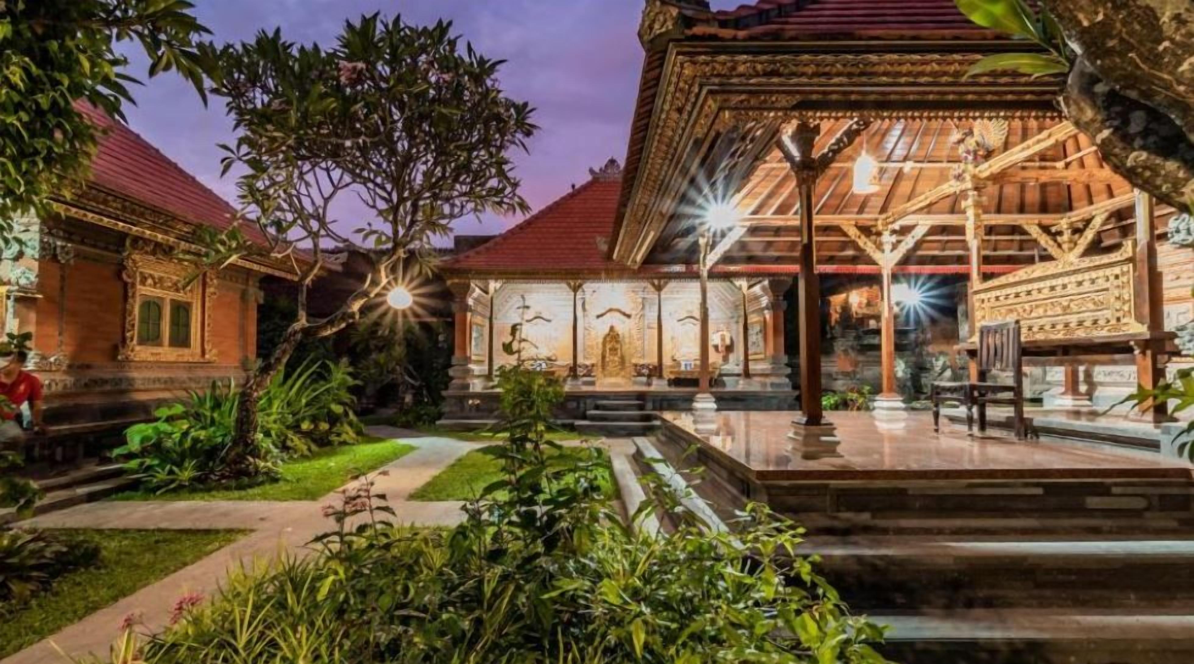 A traditional courtyard with a central pavilion, stone steps, and lush greenery.