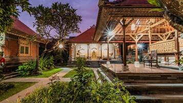 A traditional courtyard with a central pavilion, stone steps, and lush greenery.