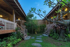 Un bâtiment en bois doté d’un porche couvert et d’un escalier en pierre menant à un jardin.