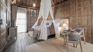 A rustic wooden room with a four-poster bed, a wooden bench, and a table with chairs. - Kirani Joglo (Celuk)