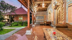 Una casa balinesa tradicional con techo de madera, suelo de baldosas y jardín.