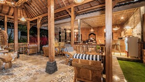 A cozy wooden interior with a bar area, seating, and a kitchen. - Kirani Joglo (Celuk)