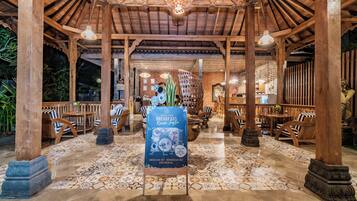 Um restaurante com interior em madeira, chão de azulejos e um letreiro anunciando café da manhã.