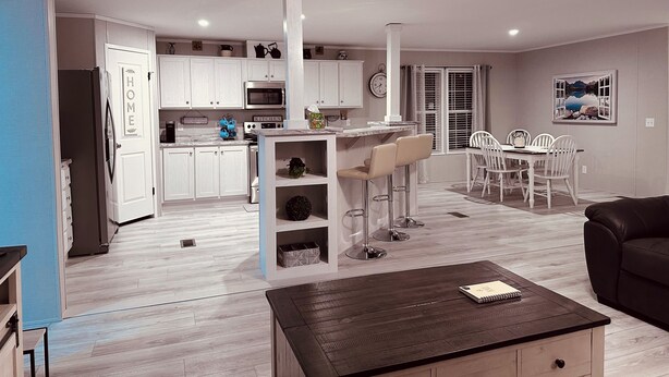 A modern kitchen with white cabinets, a microwave, and a dining area with a table and chairs. - K & M Suite is a brand-new home in a peaceful, quiet neighborhood. (Wabash)